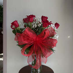 Red roses in a glass vase with a large red bow