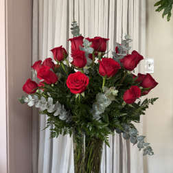 Red roses in a clear glass vase with silver eucalyptus