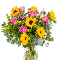 Bouquet of pink roses and yellow sunflowers in a clear glass vase