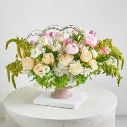 Pastel floral arrangement in a pedestal vase with arching greenery