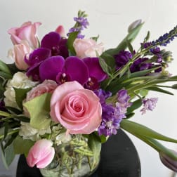 Pink roses and purple orchids in a glass vase