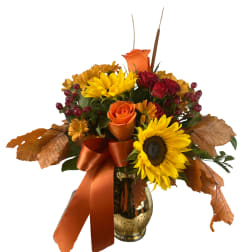 Autumn bouquet with sunflowers, roses, and a ribbon in a glass vase