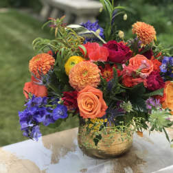Colorful mixed bouquet in a gold vase with roses and dahlias