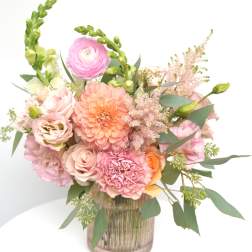 Pink and peach floral arrangement in a ribbed glass vase