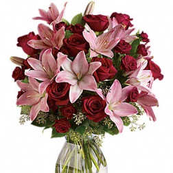 Bouquet of red roses and pink lilies in a clear glass vase