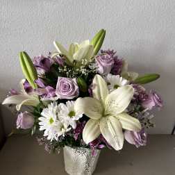 Bouquet of white lilies, lavender roses, and white daisies in a white vase