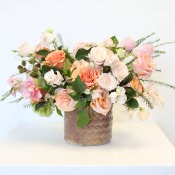 Peach and white rose bouquet in a woven basket vase