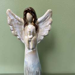Ceramic angel figurine with outstretched wings on a green wall