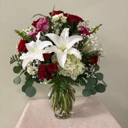 Bouquet of red roses and white lilies in a clear glass vase