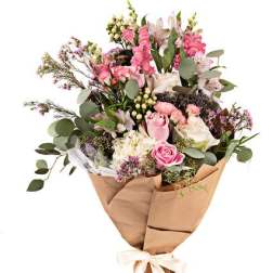 Bouquet of pink and white flowers wrapped in brown paper with a ribbon