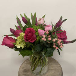 Pink roses and tulips arranged in a glass vase