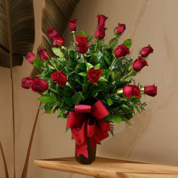 Red roses arranged in a black vase with a large red ribbon