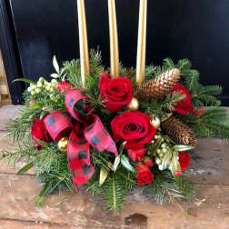 Holiday centerpiece with red roses, gold candles, and pinecones