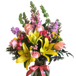 Mixed bouquet of yellow lilies, pink roses, and purple flowers in a glass vase
