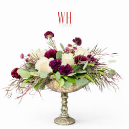 White and purple floral arrangement in a silver pedestal vase