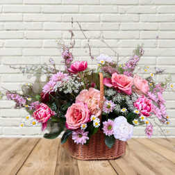 Pink and white mixed flower arrangement in a wicker basket