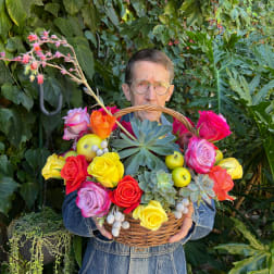 Basket of colorful roses and succulents held by a man outdoors