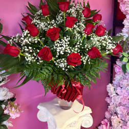 Red roses arranged in a clear vase with white baby's breath
