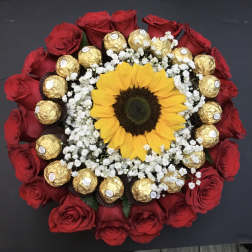 Round bouquet of red roses with a sunflower center, baby’s breath, and gold chocolates