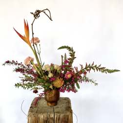 Tropical floral arrangement in a copper vase with orange bird-of-paradise and pink blooms