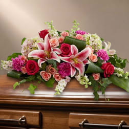 Pink and white floral spray on a wooden casket