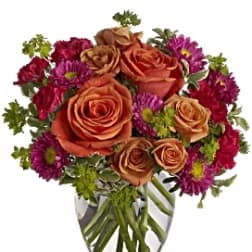 Bouquet of orange roses and purple daisies in a clear glass vase