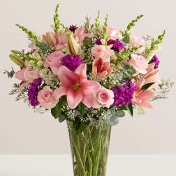 Pink lilies and roses arranged in a clear glass vase