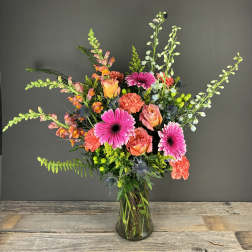 Mixed bouquet of pink gerbera daisies and orange roses in a glass vase