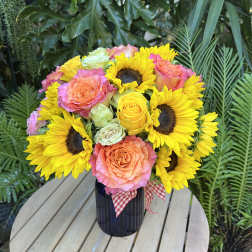 Bouquet of yellow sunflowers and peach roses in a dark vase