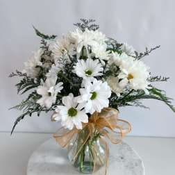 White daisy bouquet in a glass vase with a gold ribbon