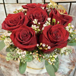 Red roses arranged in a white hat box with small white filler flowers
