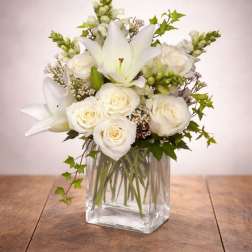 White roses and lilies arranged in a clear glass vase