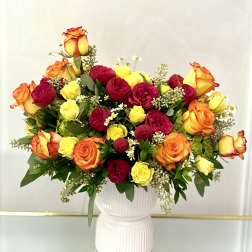 Bouquet of red, yellow, and orange roses in a white vase