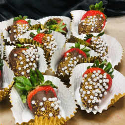 Chocolate-covered strawberries in paper cups with white and gold sprinkles