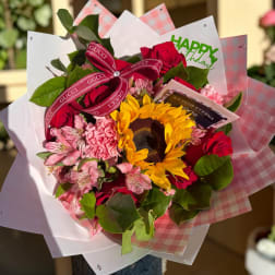 Bouquet of red roses, pink flowers, and a sunflower with a ribbon