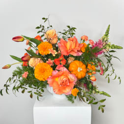 Bright mixed floral arrangement in a white vase with orange and pink blooms