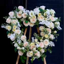 Heart-shaped floral wreath of pale roses on a wooden easel