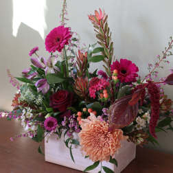 Mixed floral arrangement in a white wooden box with pink and peach blooms