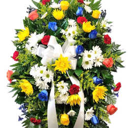 Standing floral spray with multicolored roses, daisies, and a white ribbon