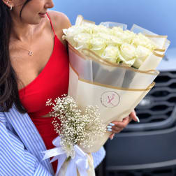 Bouquet of white roses wrapped in cream paper with a white ribbon