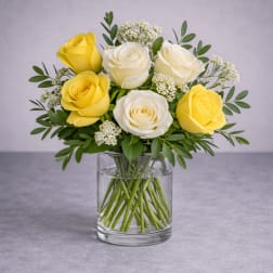 Yellow and white roses arranged in a clear glass vase