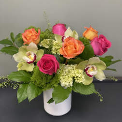 Pink and orange roses with orchids in a white vase