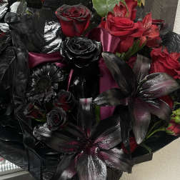 Bouquet of red and black roses with dark lilies in a glass vase