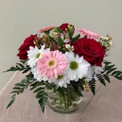 Bouquet of red roses and pink gerbera daisies in a clear glass vase