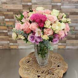 Bouquet of pink, cream, and lavender roses in a clear glass vase
