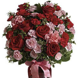 Red roses and pink carnations in a red vase with a pink ribbon
