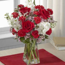 Red roses and white flowers arranged in a clear glass vase