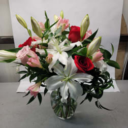 Bouquet of red and pink roses with white lilies in a glass vase