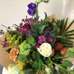 Mixed bouquet with roses, orchids, and other flowers wrapped in brown paper