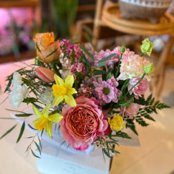 Mixed bouquet of pink, yellow, and white flowers in a white box